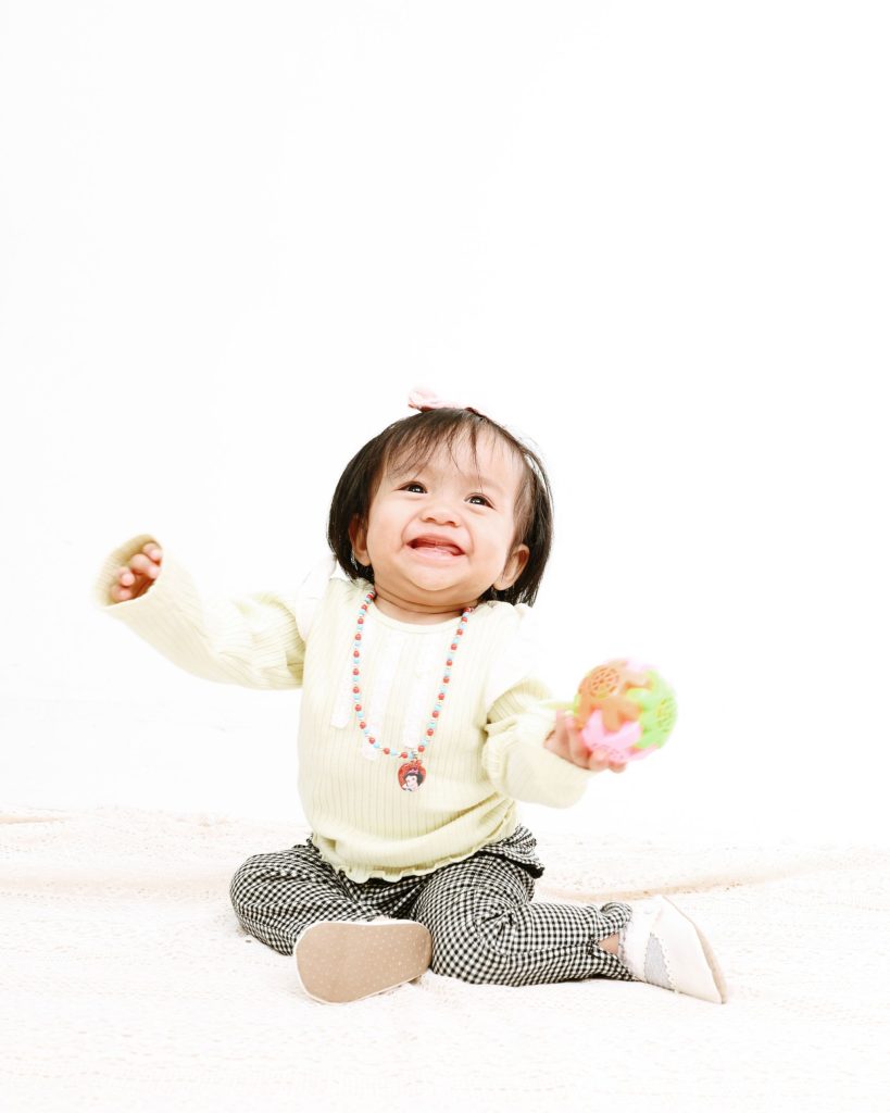 Baby laughing with a toy ball, first birthday photoshoot at The Cade & Co studio Cyberjaya