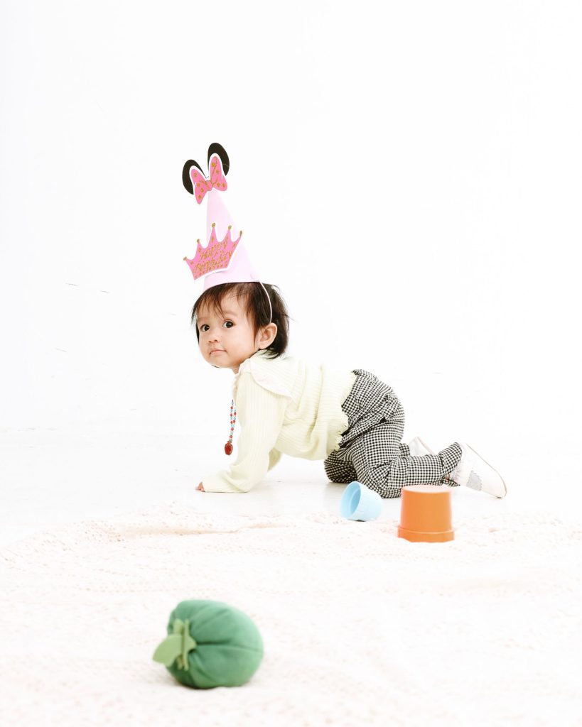 Baby crawling in a party hat, first birthday photoshoot at The Cade & Co studio Cyberjaya