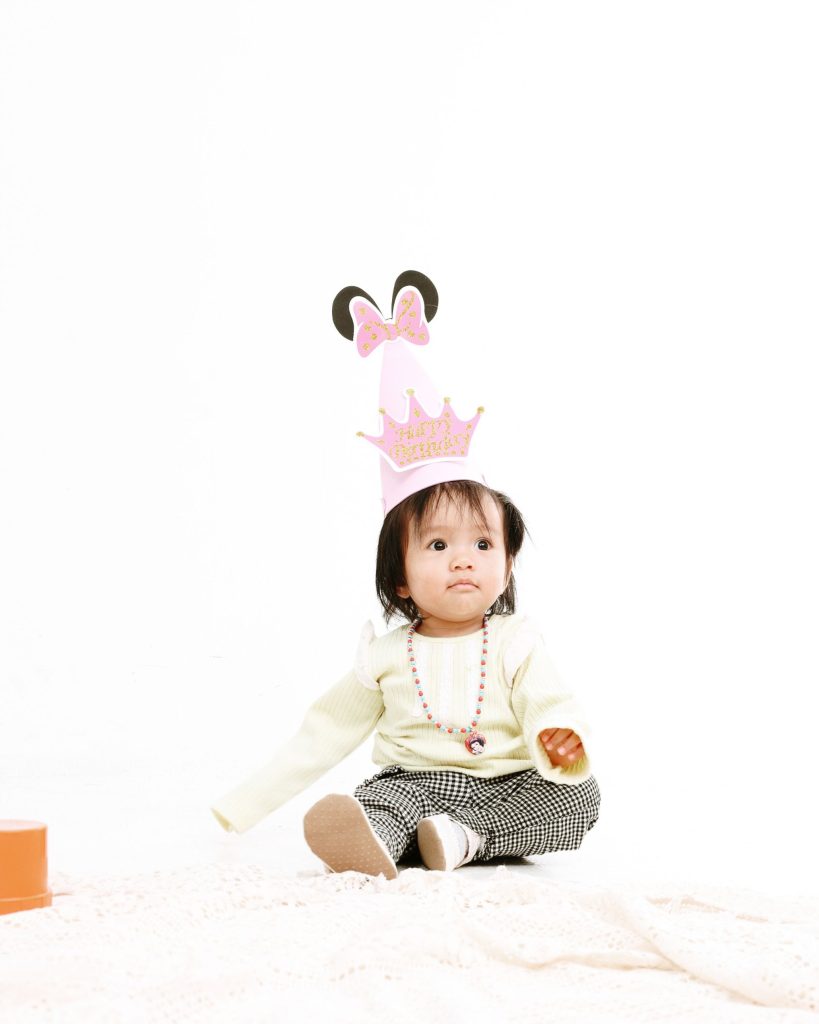 Curious baby in a party hat, first birthday photoshoot at The Cade & Co studio Cyberjaya
