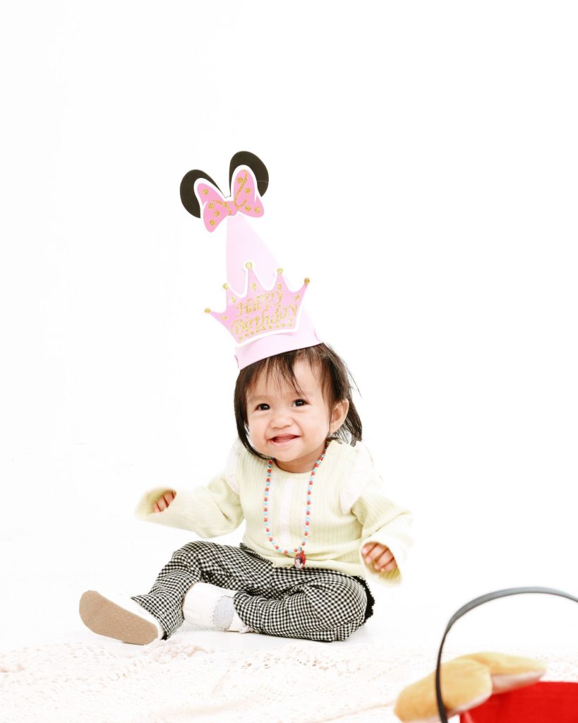Baby smiling in a party hat, first birthday photoshoot at The Cade & Co studio Cyberjaya