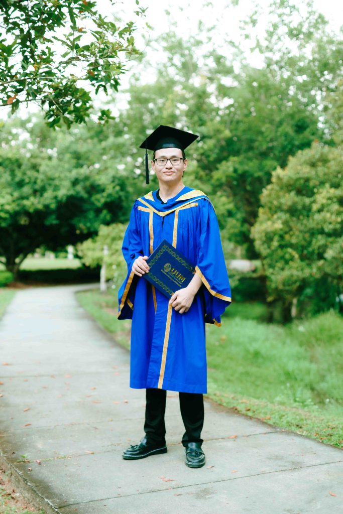 Tan Kim in UUM graduation robe on a garden path, Kepong Botanical Garden